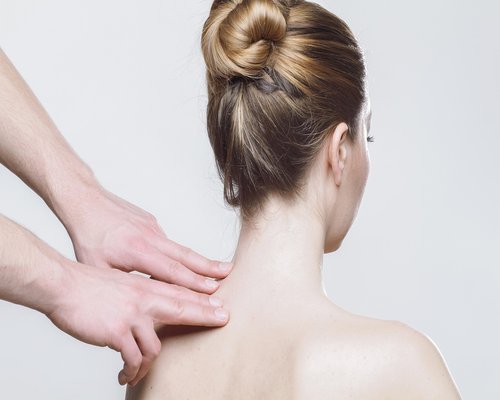 Person stretching their neck and shoulders lightly while sitting at a desk